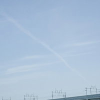 線路の上空を通過するひこうき雲の写真