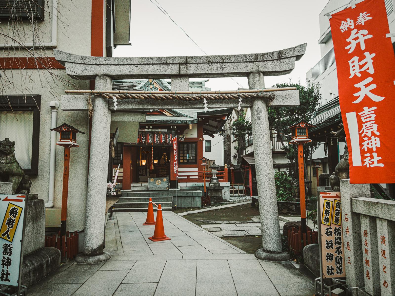 石造の鳥居をくぐる吉原神社の参道。奥に赤い幟の掛かった社殿が見える。