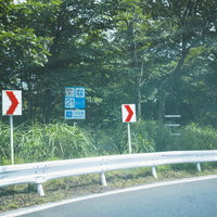 栃木県いろは坂のカーブ標識とガードレールの写真