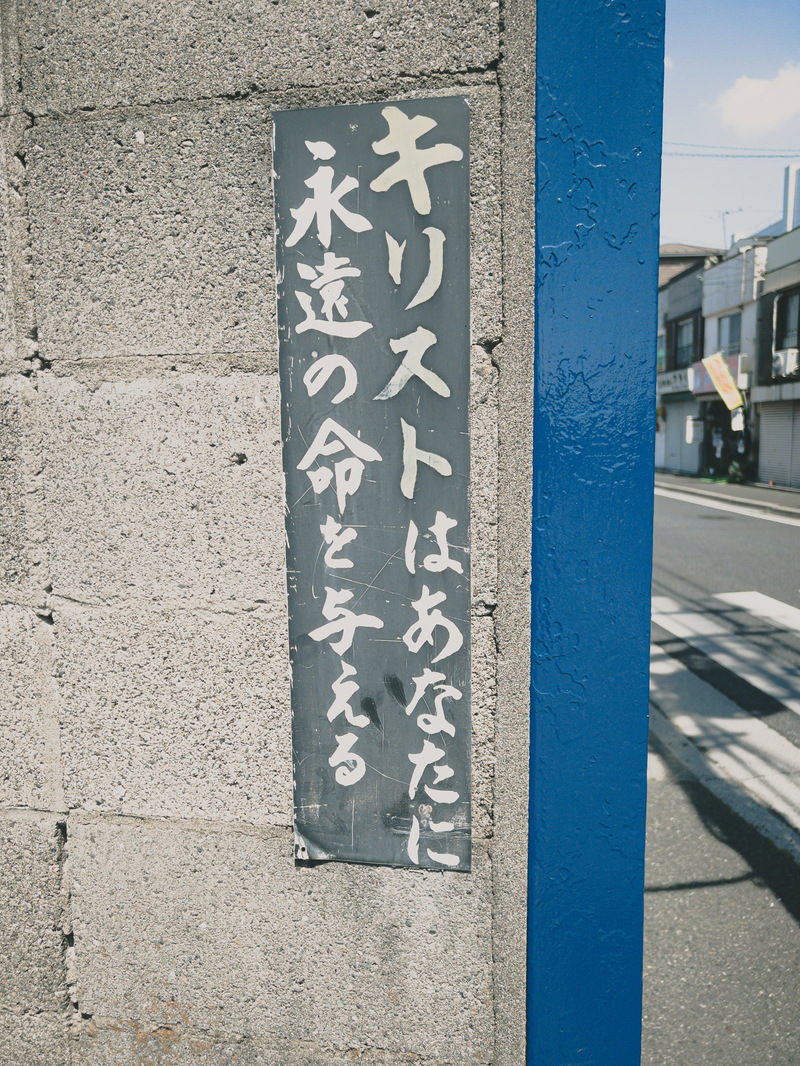 コンクリート壁面にキリストはあなたに永遠の命を与えると縦書きで書かれた宗教的な看板