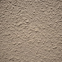 粗い凹凸が広がるモルタル壁のテクスチャーの写真