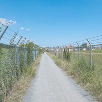 両側フェンスが続く入間基地沿いの一本道、自衛隊施設の周辺風景の写真