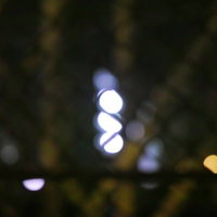 フェンスの向こうに浮かぶ不気味な光と街灯の写真