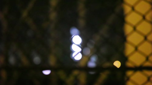 フェンスの向こうに浮かぶ不気味な光と街灯