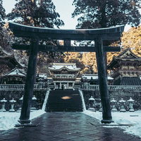 雪が積もった大きな黒い鳥居と奥の本殿が見える日光東照宮の写真