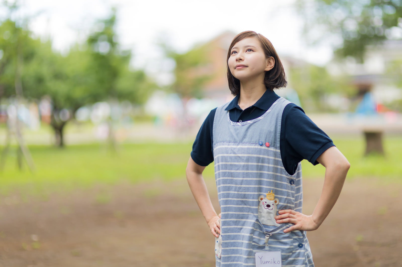エプロン姿で腰に手を当て、やる気を見せる女性介護士［モデル：yumiko］