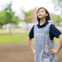 エプロン姿で張り切る介護士の女性 屋外でやる気に満ちた表情の写真