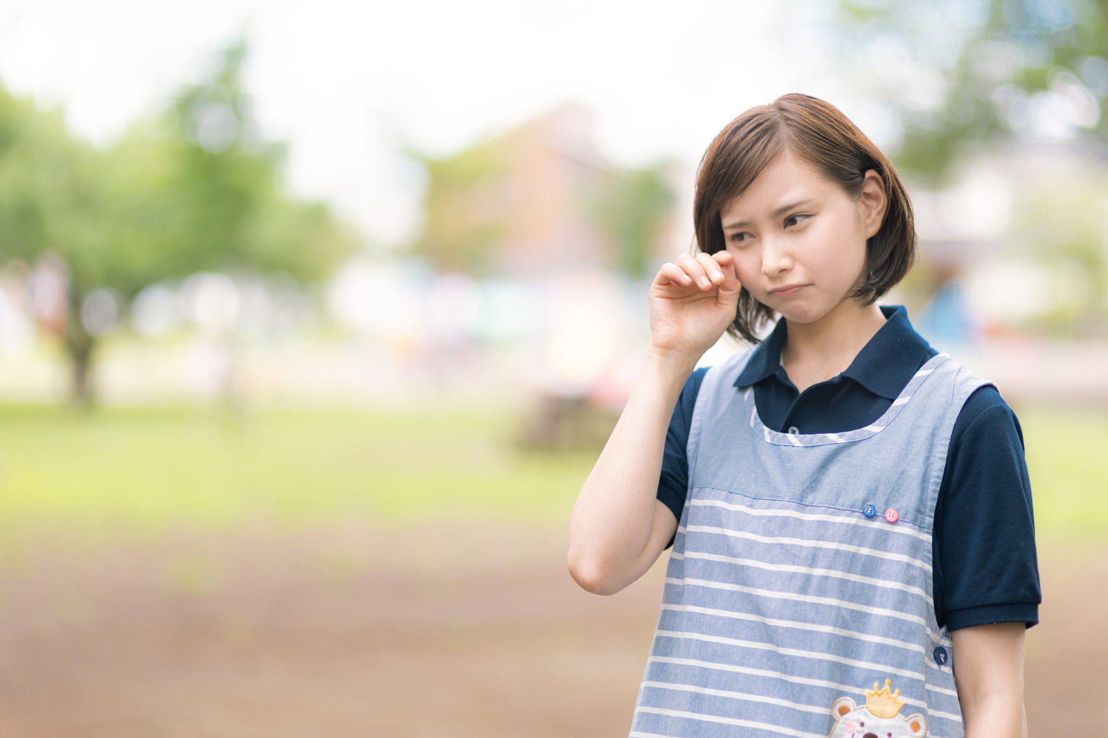 手で顔を覆い涙を流している介護士の女性［モデル：yumiko］