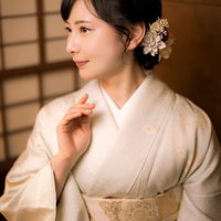 白い着物に金色の帯を締めた女将の横顔、和室で微笑むの写真