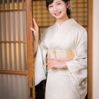 玄関を開けてお出迎えする着物姿の女将の写真