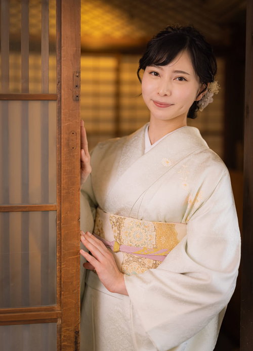 そっと旅館の扉を開ける着物姿の女将が客をお迎えする