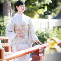 神社の境内を薄紫色の着物で歩く女性の参詣風景の写真