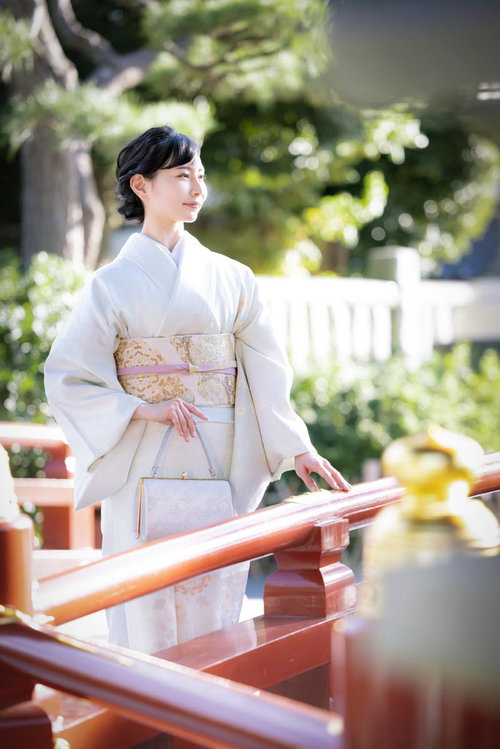 神社の境内を薄紫色の着物で歩く女性の参詣風景