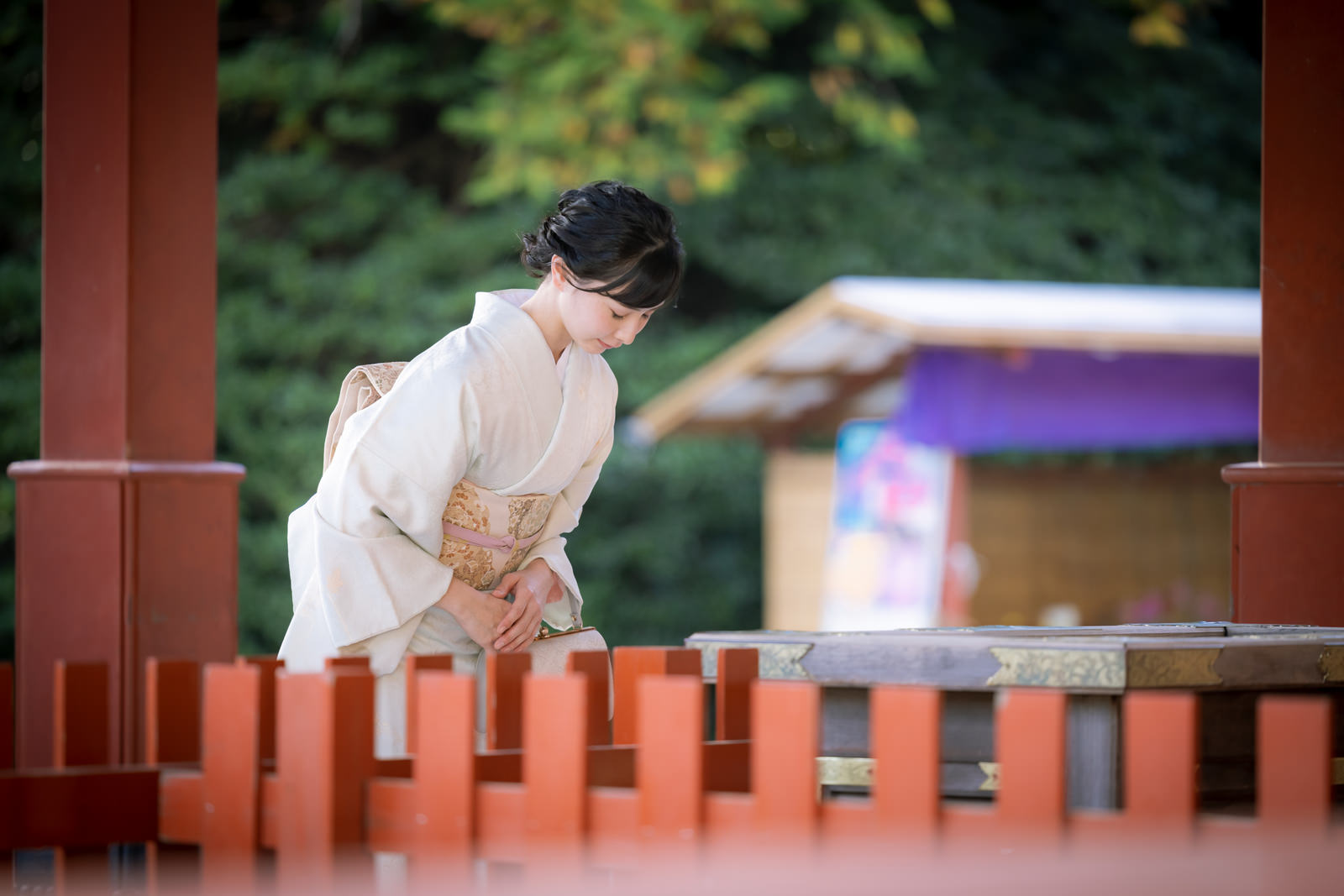 神社で白い着物を着た女性が深くお辞儀をしている様子［モデル：yumiko］