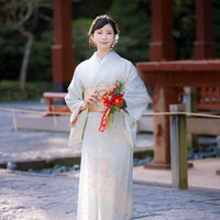 正月飾りを持った着物姿の女性が参拝に訪れた境内で立つの写真