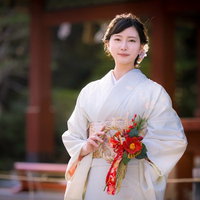 正月飾りのある神社の境内で微笑む着物女性の参拝風景の写真