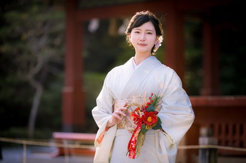 正月飾りのある神社の境内で微笑む着物女性の参拝風景