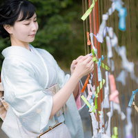 神社の境内でおみくじを結ぶ着物姿の女性の写真