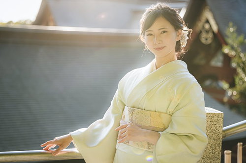 散策中の笑顔の着物の女性、淡い黄色の上品な和装姿