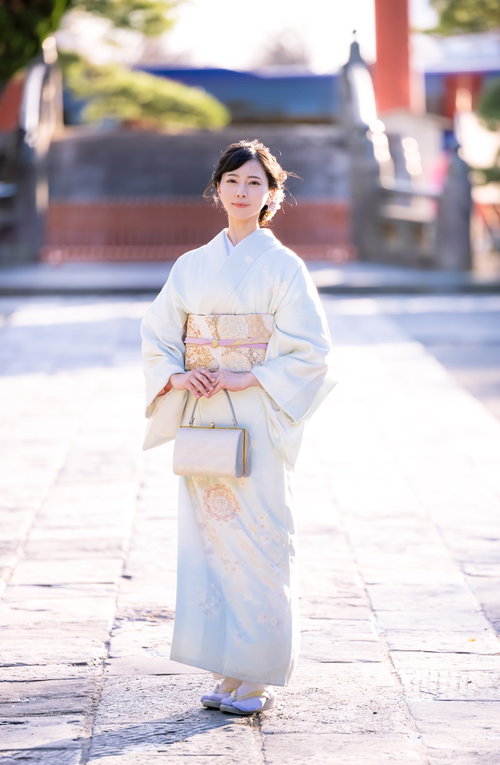 神社の境内を歩む着物姿の女性の全身ショット