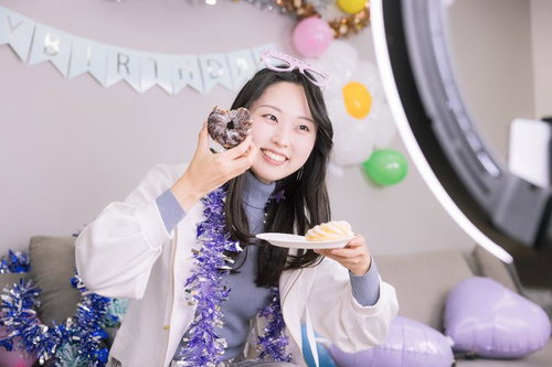 生誕祭でチョコレートのフレンチクルーラーを食べながら生配信する女性