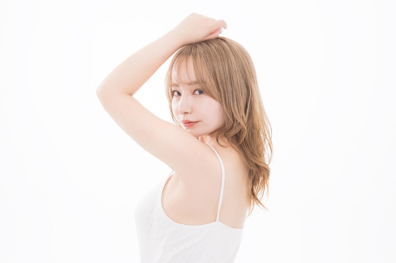 脇を上げて振り返る美肌の女性がキャミソール姿で横向きに立っている［モデル：yuria］