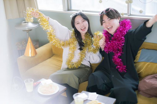 男女が金銀のガーランドでホームパーティーを盛り上げる