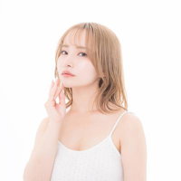 頬に手を当てる透明感溢れる美肌女子のスキンケアの写真