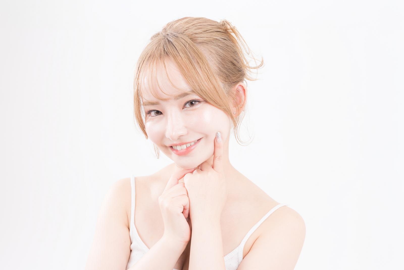 頬に手を添えて微笑む若い女性［モデル：yuria］