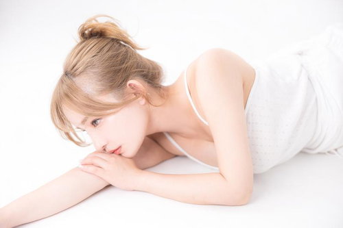 白いキャミソール姿でうつむく艶やか肌の女性