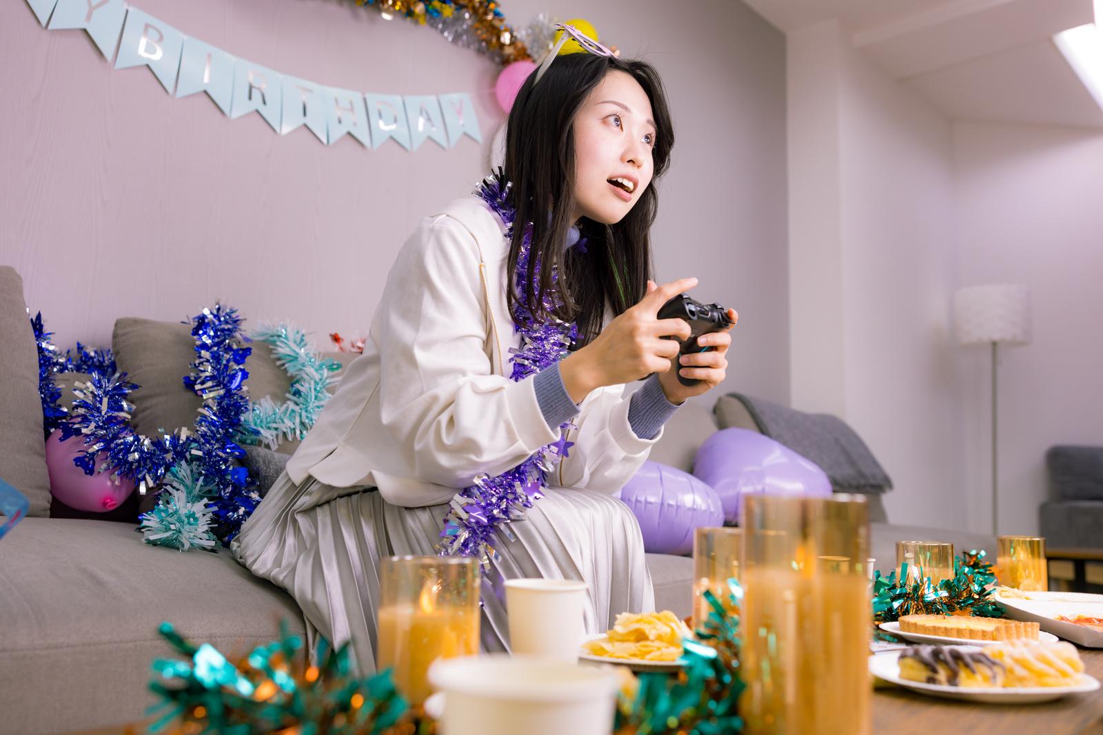 生誕祭パーティーでゲームコントローラーを握る女性［モデル：吉屋ゆり］