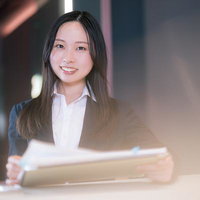 会議室で資料を見てほほ笑む女性営業職の書類確認シーンの写真