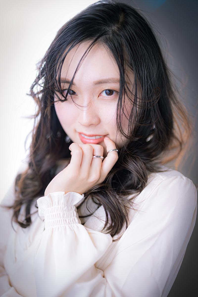白いブラウスを着た女性が頬に手を当てながら微笑むポートレート写真［モデル：吉屋ゆり］