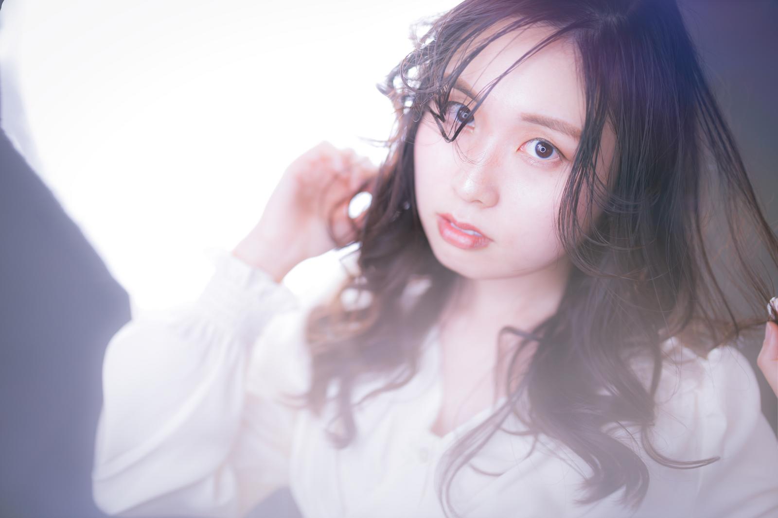 眼鏡をかけたゆるふわ巻き髪の女性が正面を向く［モデル：吉屋ゆり］