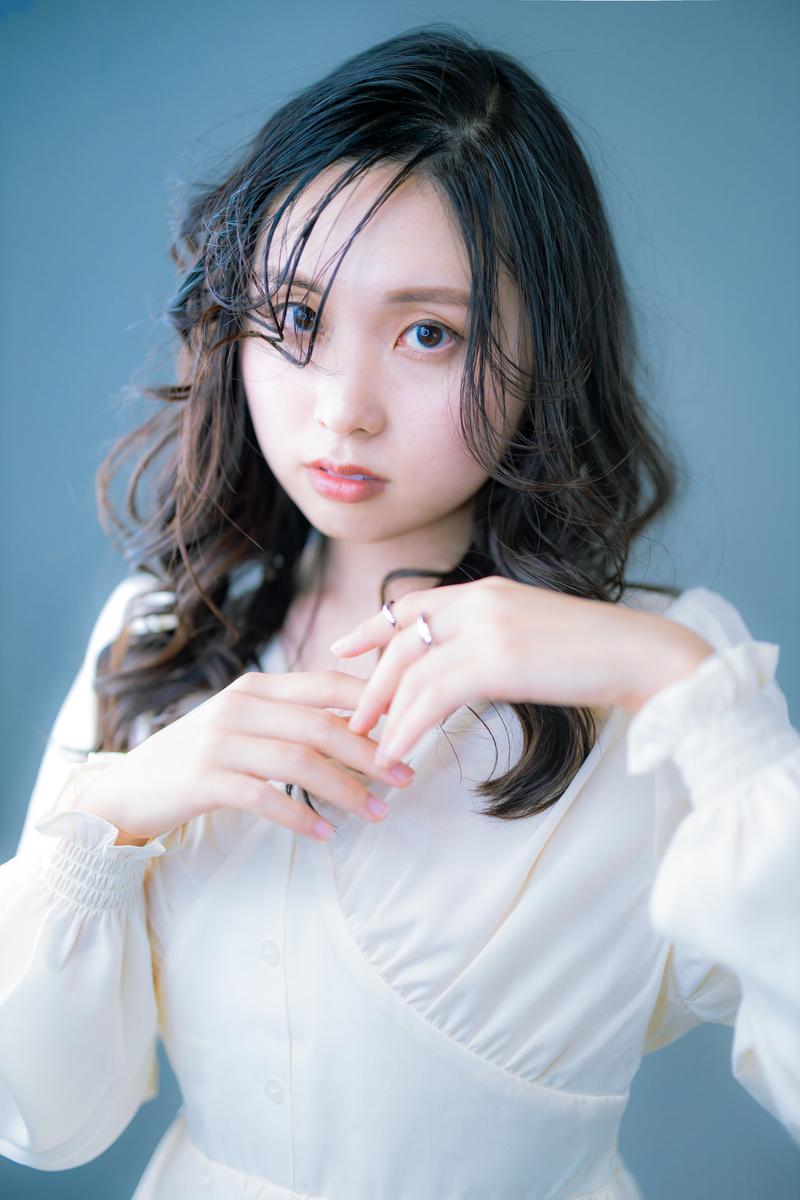 白いシャツを着た黒髪巻き髪の若い女性が、胸元で両手を重ねてシルバーの指輪を見せながら正面を向いている［モデル：吉屋ゆり］