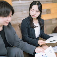 オフィスでビジネス資料を確認する男女の打ち合わせ風景の写真