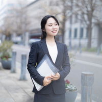 書類を抱えて外回りに向かうスーツ姿のOLの写真