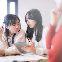 カンファレンス中にタブレットで今日のランチを真剣に議論するOLふたりの写真