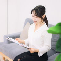 ソファーに座って資料を眺める女性の写真