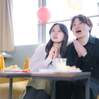 ホームパーティーで風船の下、映画を見るカップルの写真