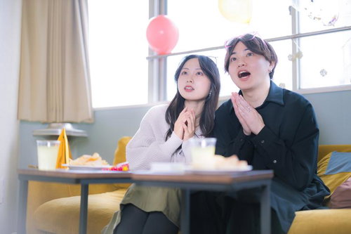 ホームパーティーで風船の下、映画を見るカップル