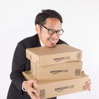 ポチリ過ぎて感覚がおかしくなった会社員がダンボール箱を抱えて喜ぶの写真