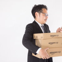 届いた商品と発注内容をスマートフォンで確認する会社員の写真