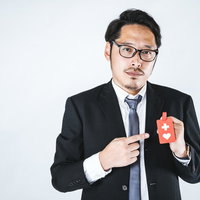赤いヘルプマークを持つスーツ姿の会社員男性の写真