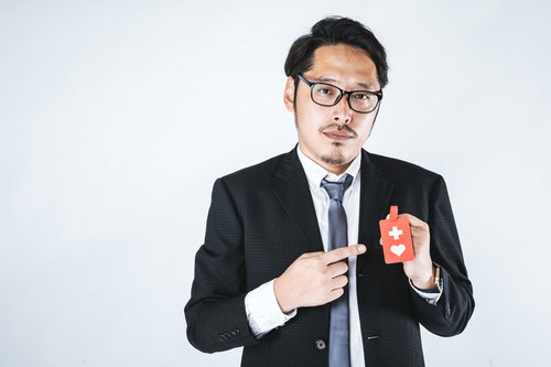 赤いヘルプマークを持つスーツ姿の会社員男性