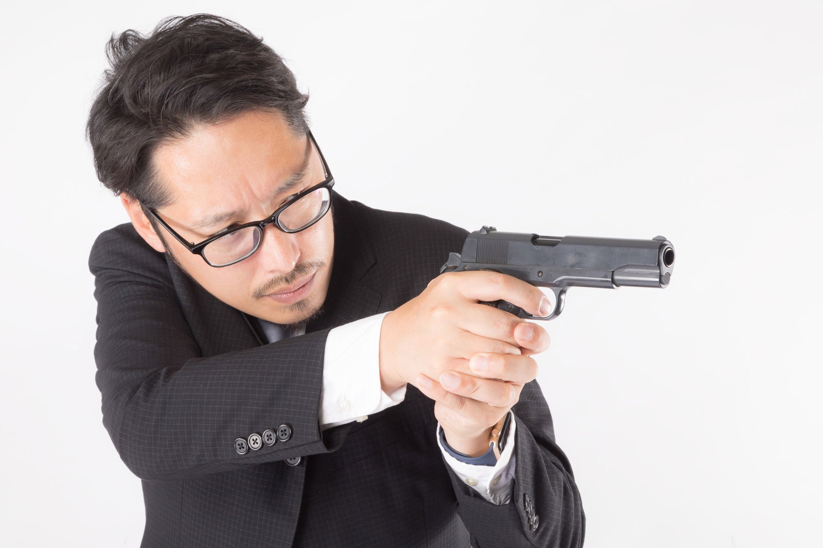 黒いスーツを着た眼鏡の男性が両手で拳銃を構えている様子［モデル：ゆうせい］