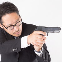 拳銃を向けるスーツ姿の男性会社員の写真