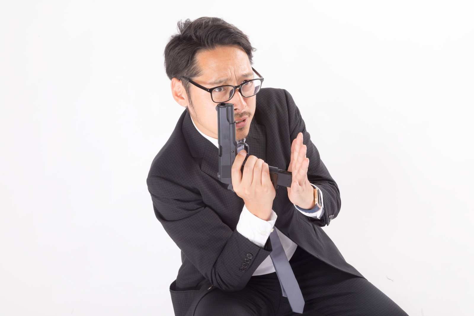 黒いスーツを着た男性が拳銃の弾倉を装填している写真［モデル：ゆうせい］