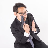 スムーズに拳銃の弾倉を装填するスーツ姿の会社員の写真