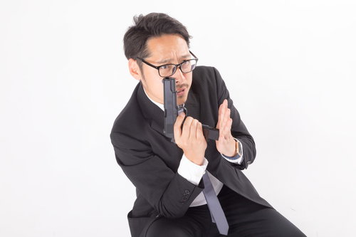 スムーズに拳銃の弾倉を装填するスーツ姿の会社員